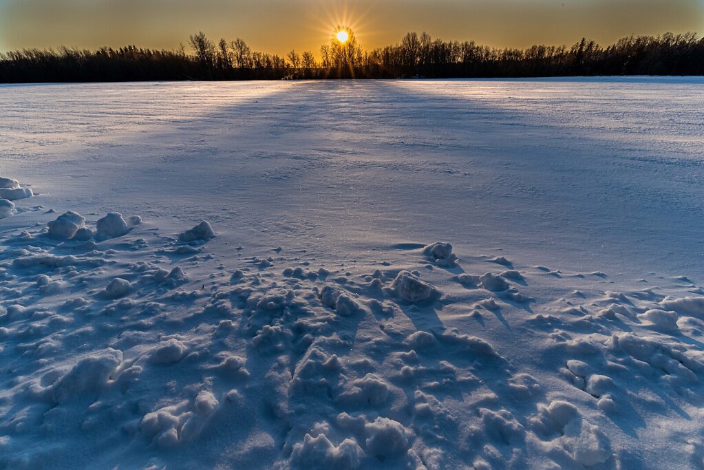 Loojuv päike üle lumise põllu